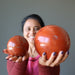 woman holding two red jasper balls