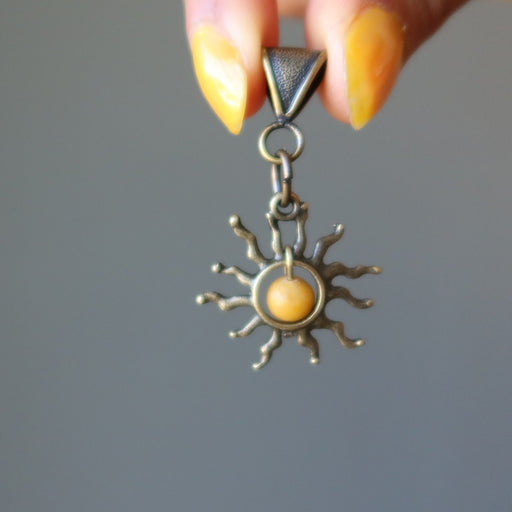 hand holding yellow jasper sun pendant