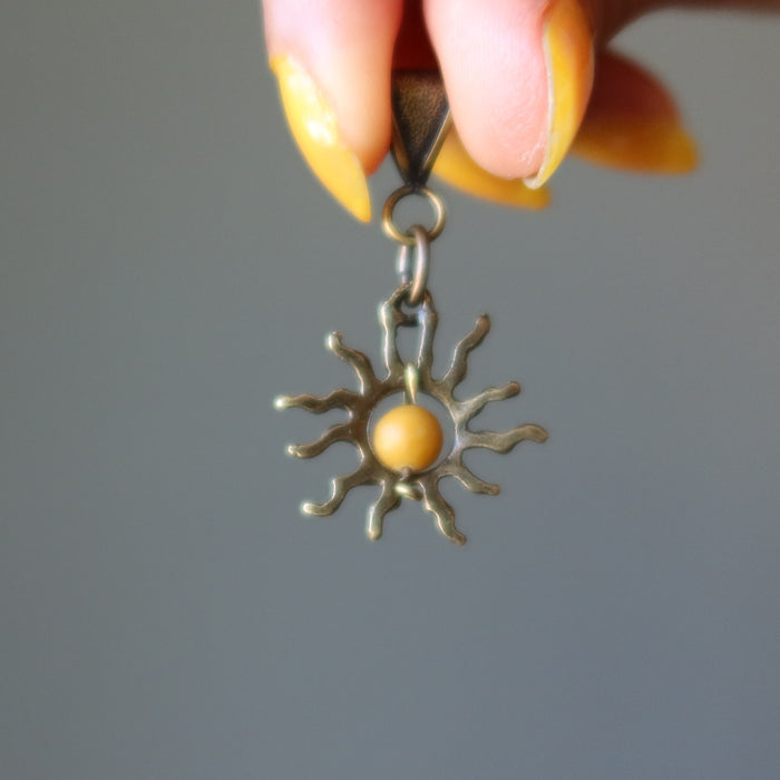 hand holding yellow jasper sun pendant 