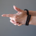 pair of hands wearing 3 black jet stone round beaded stretch bracelets