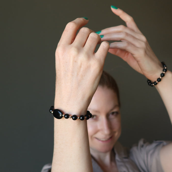 jamie of satin crystals with hands raised wearing black jet stone and copper beaded bracelets
