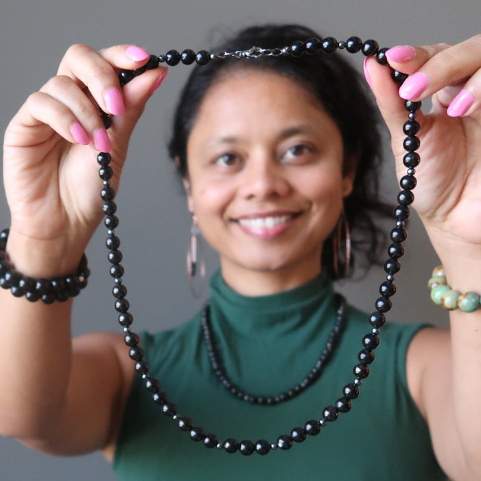 sheila of satin crystals holding up a black jet stone beaded necklace