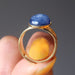 hand holding blue kyanite oval in gold adjustable ring