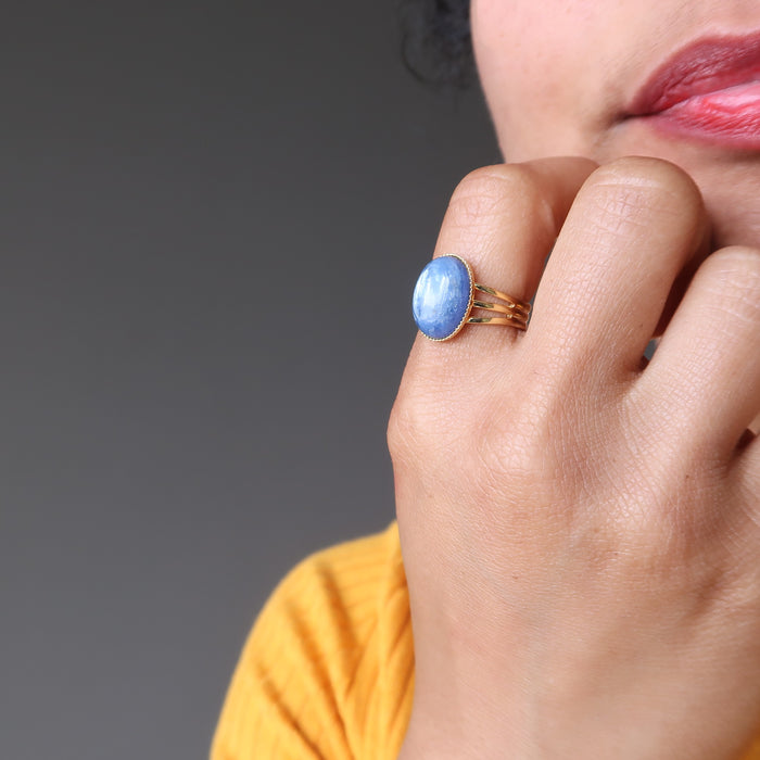 hand wearing blue kyanite oval in gold adjustable ring