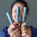 sheila of satin crystals holding up three blue kyanite massage wands