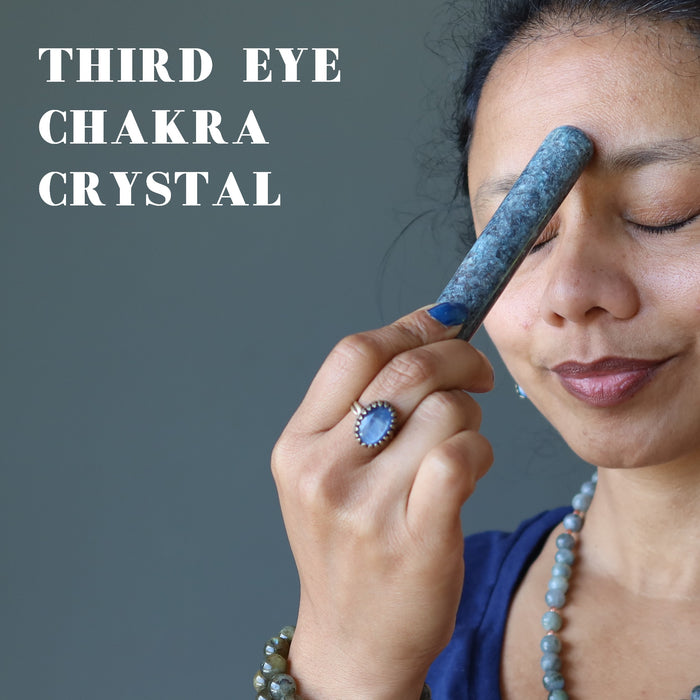 sheila of satin crystals holding up a blue kyanite massage wand to her third eye chakra