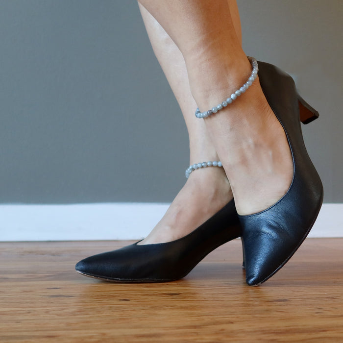 pair of feet wearing labradorite anklets on each ankle