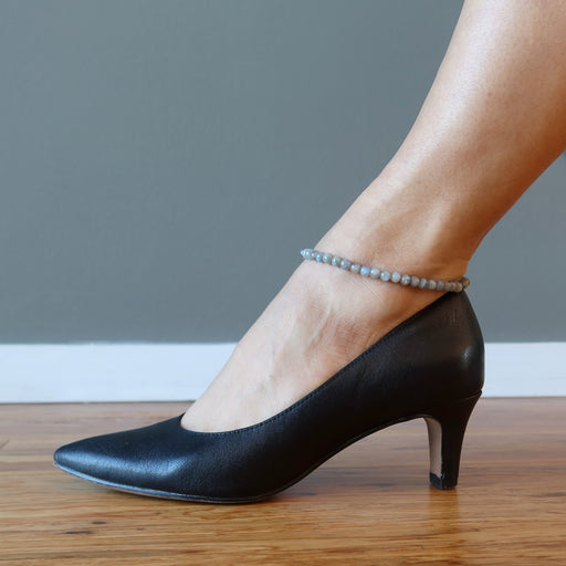 foot in black high heels wearing labradorite anklet