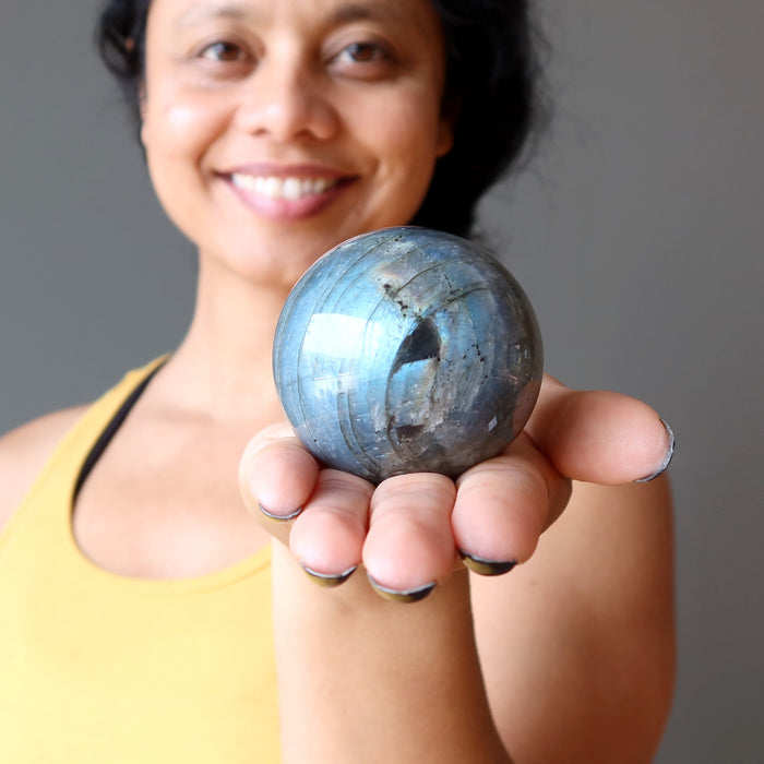 sheila of satin crystals holding a blue flash labradorite sphere