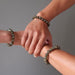 three hands clasped all wearing round labradorite beaded stretch bracelet