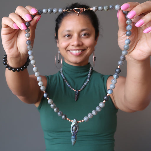 sheila of satin crystals holding up a labradorite goddess necklace