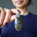 hand holding large labradorite pendant in front of chest