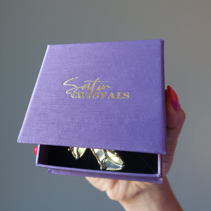 hand holding labradorite pendant in purple satin crystals gift box