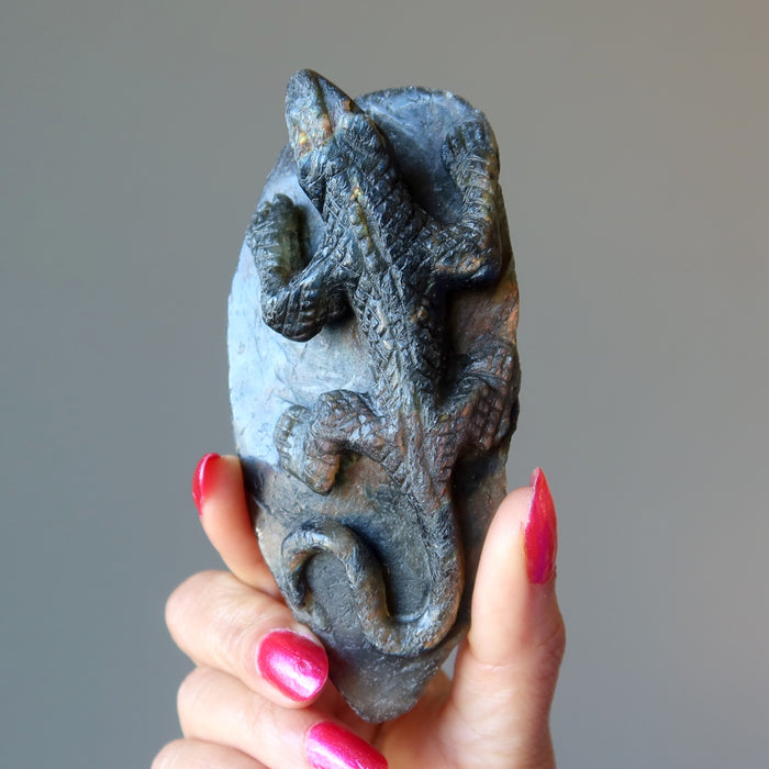 sheila of satin crystals holding up a labradorite lizard carving