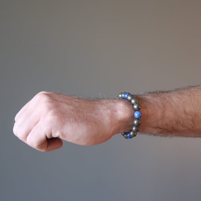 man's hand wearing lapis lazuli and pyrite round beaded stretch bracelet