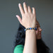 woman with arm in front of her face wearing lapis lazuli and pyrite round beaded stretch bracelet