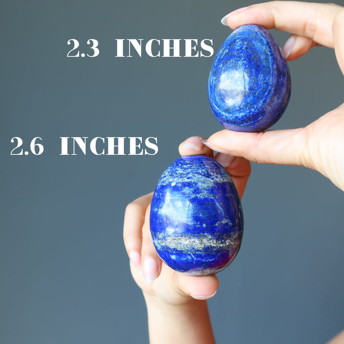 hands holding two lapis eggs to see size difference