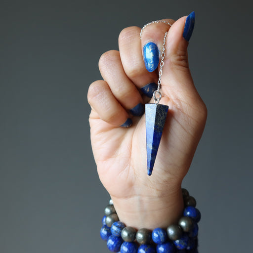 hand holding lapis lazuli crystal healing sterling silver pendulum