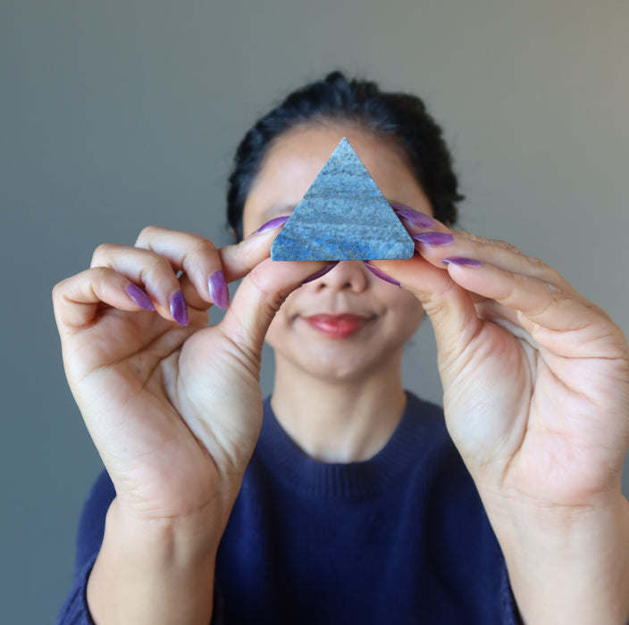 hand holding lapis pyramid over third eye chakra