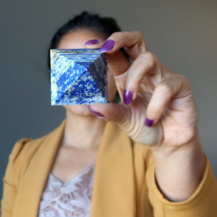 woman holding lapis pyramid in front of her face