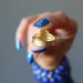 hand holding lapis lazuli gemstone in gold tone adjustable ring showing the adjustable back
