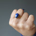 hand making fist wearing lapis lazuli gemstone in gold tone adjustable ring