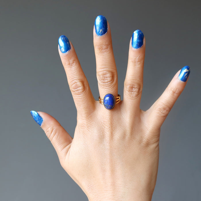 spread hand wearing lapis lazuli gemstone in gold tone adjustable ring