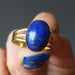 hand holding lapis lazuli gemstone in gold tone adjustable ring