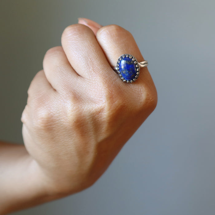 fisted hand wearing lapis lazuli sterling silver ring adjustable jewelry on the pointer finger