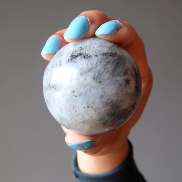 hand holding up a silver labradorite sphere