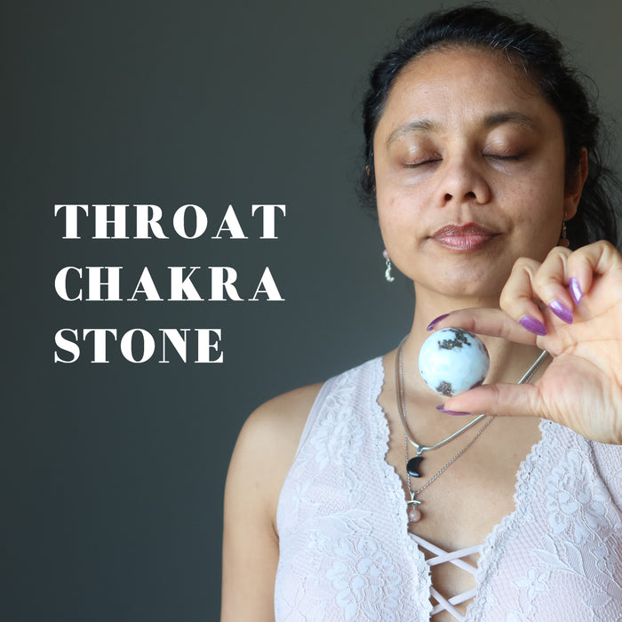hand holding larimar sphere at throat chakra
