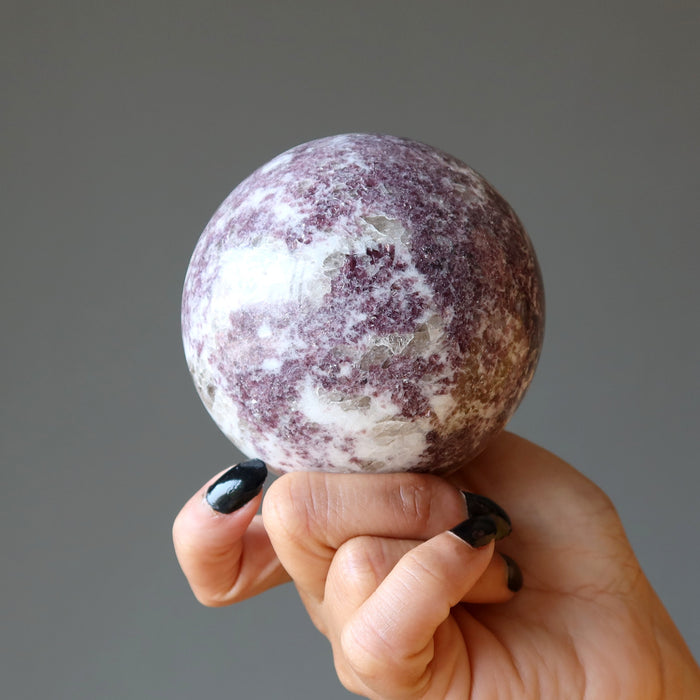 hand holding quartz lepidolite sphere