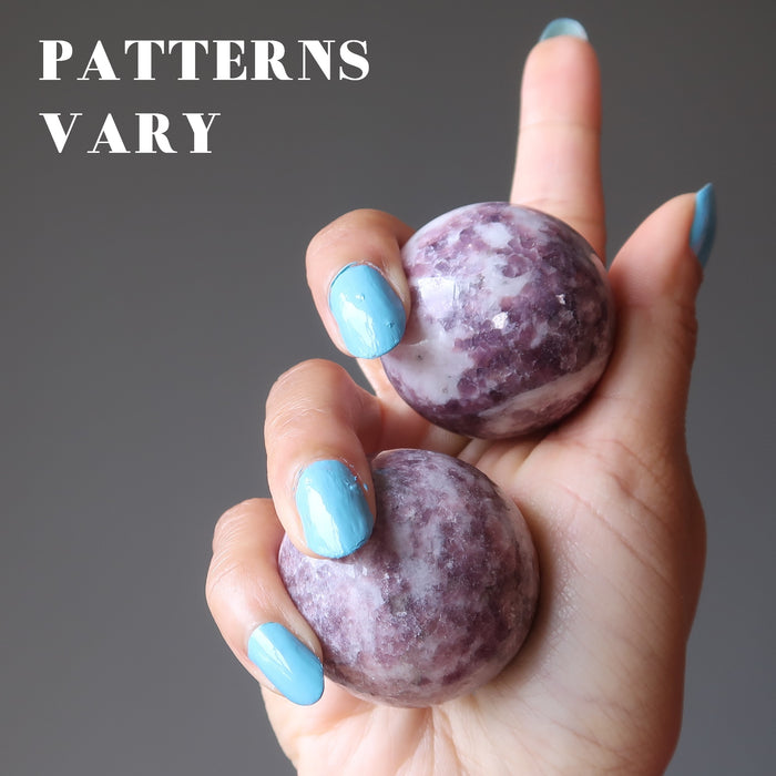 hand holding two lepidolite spheres to show patterns vary