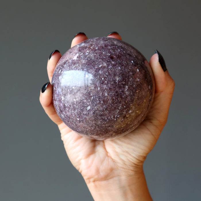purple lepidolite sphere in palm of hand