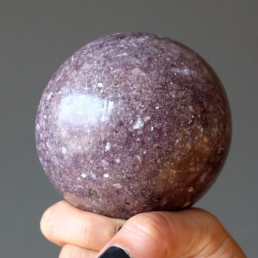 purple lepidolite sphere on hand