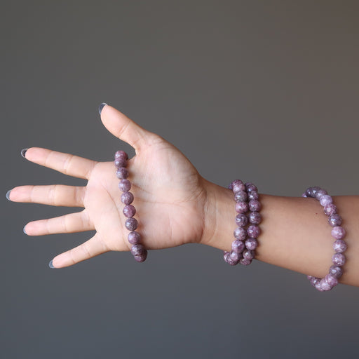An arm showcasing four purple lepidolite stretch bead bracelets