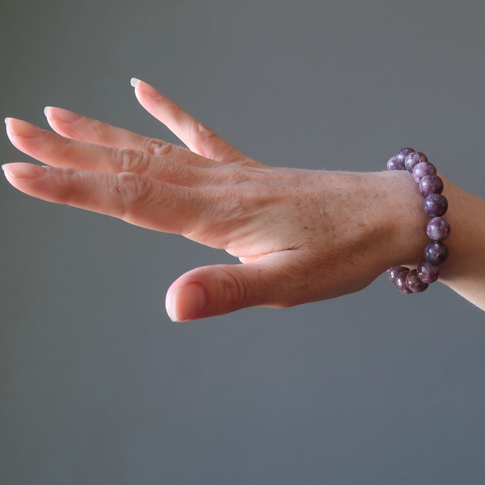 A lady's hand outstretched to display the round beaded purple lepidolite stretch bracelet