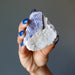 hand holding rough purple lepidolite on white quartz cluster