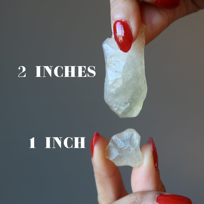 hand holding two libyan desert glass crystals to show size difference between 2 inches and 1 inch