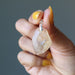 hand holding yellow libyan desert glass raw pendant
