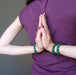 female model with hands in prayer at her back wearing three green malachite stretch bracelets