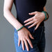 woman with hands at torso wearing malachite bracelets