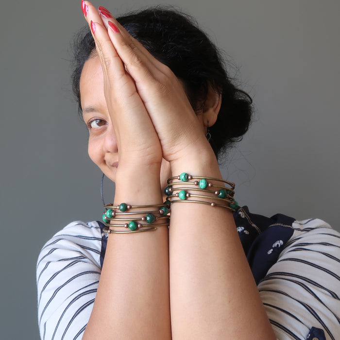 Sheila of Satin Crystals with hands in prayer to show both arms adorned with the green malachite gemstone memory wire bracelet