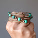 A hand holding the Satin Crystals Malachite coil bracelet