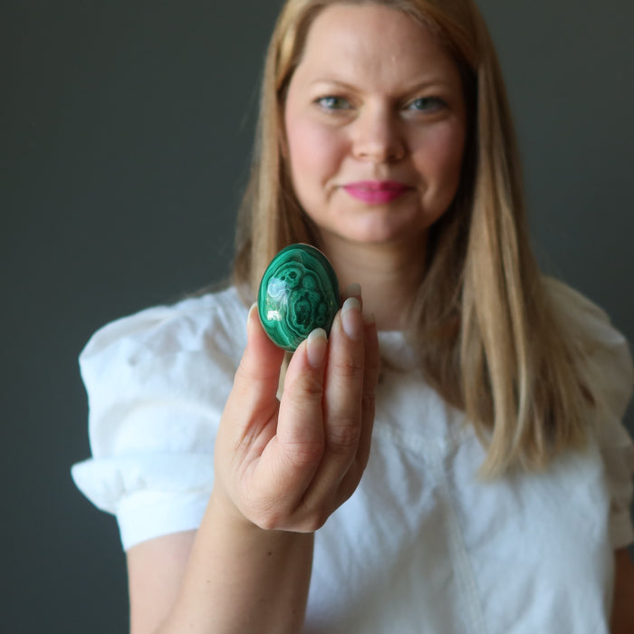 female model holding malachite egg at her heart chakra