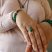 hand wearing green malachite oval copper ring with other malachite jewelry
