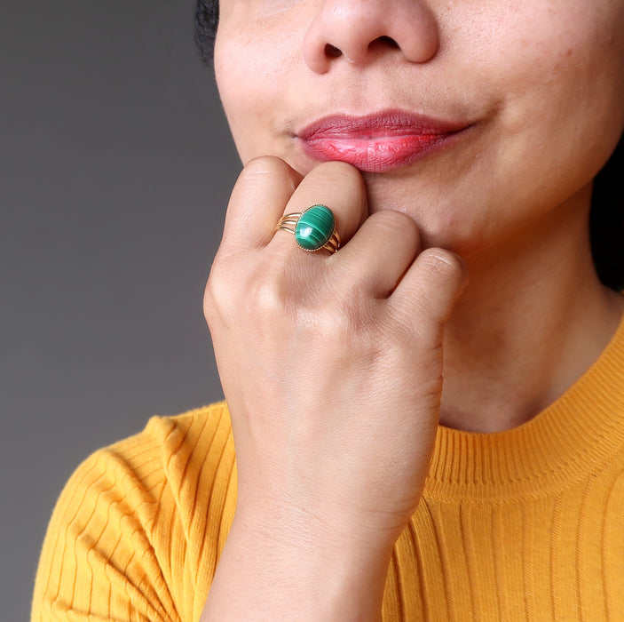 hand on chin wearing green oval malachite in gold adjustable ring