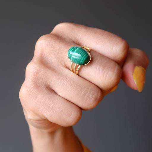 fist wearing green oval malachite in gold adjustable ring