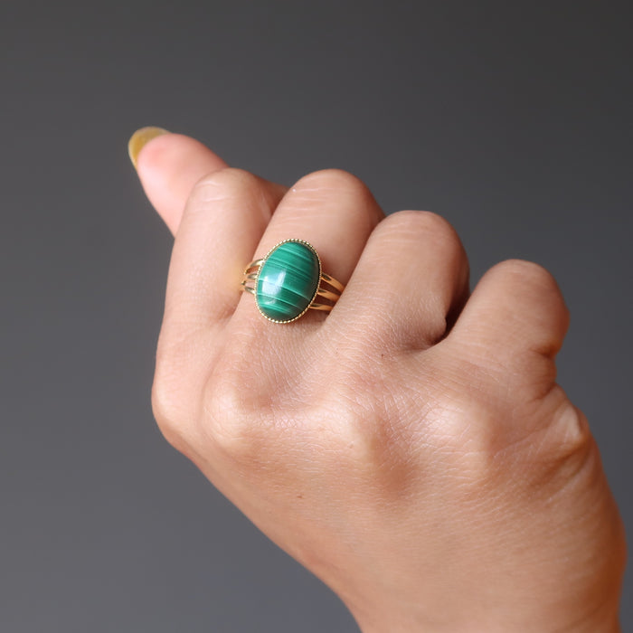 hand wearing green oval malachite in gold adjustable ring