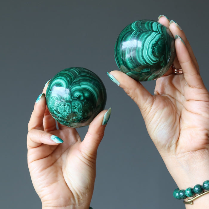 hands holding a malachite sphere